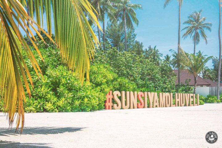 Sun Siyam Olhuveli Hashtag-Schild mit Palmen und Strand.