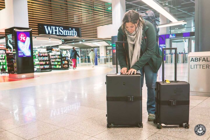 Frau schliesst Schloss von Koffern am Airport.