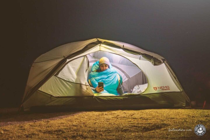 Frau sitzt bei Nacht im Campingzelt.