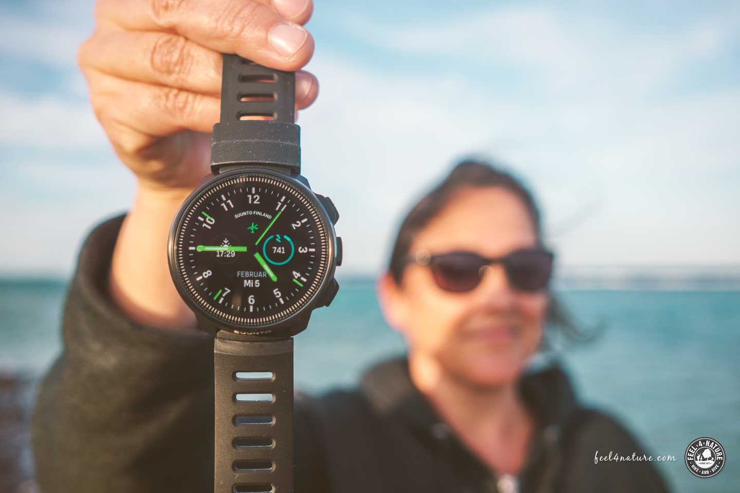 Frau am Meer hält Suunto Ocean Tauchcomputer Smartwatch in die Kamera.