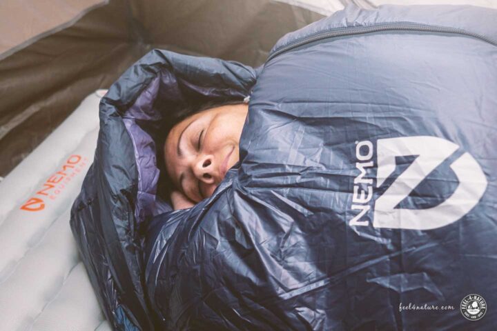 Frau liegt im Zelt mit dem Nemo Soul Schlafsack auf einer Isomatte.