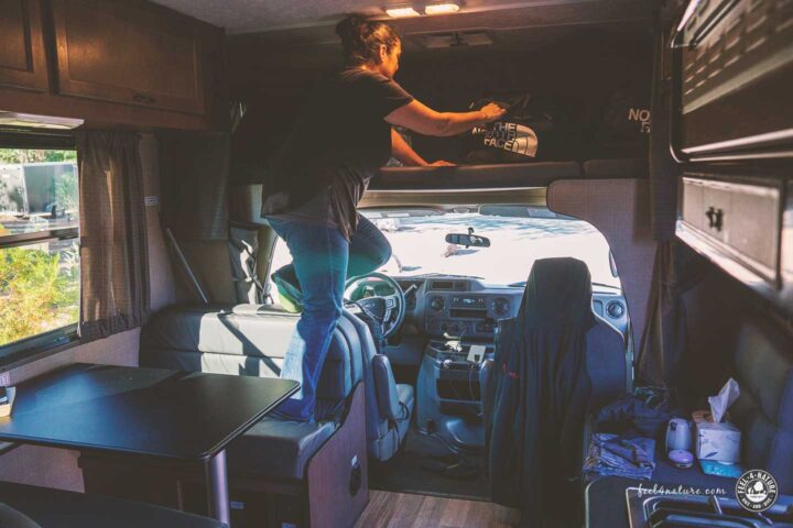 Frau legt Sachen in den Alkoven des C25 Wohnmobils.